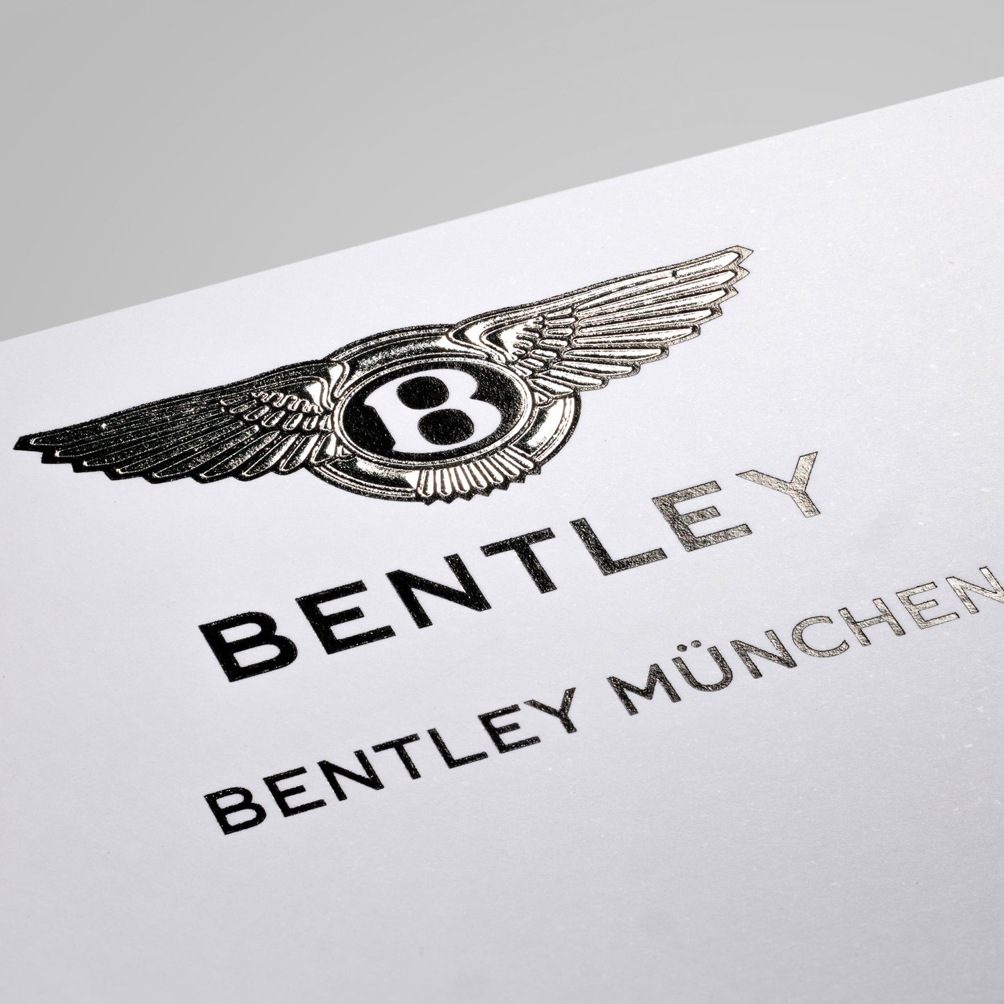 Reliefgeprägte Visitenkarte für Bentley München, silberfarbener und schwarzer, glänzender Druck auf weissem Karton.